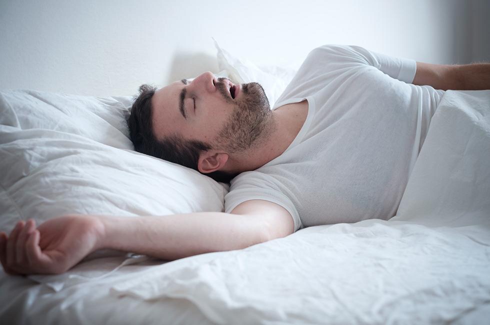 A young male with a beard lying on his back and breathing with his mouth open, which is a clear sign of sleep apnea in Midland