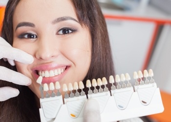 Woman's smile compared with tooth color chart