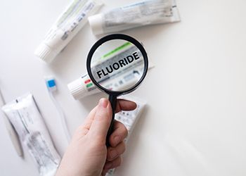 Magnifying glass zooming in on toothpaste with Fluoride listed as an ingredient