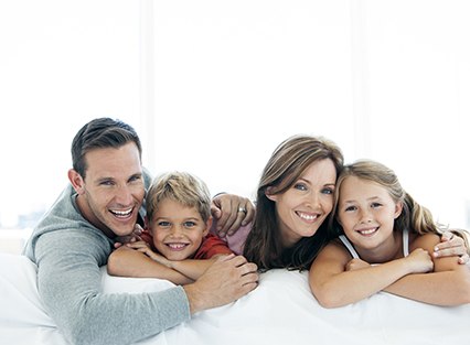 Smiling family of four against white background