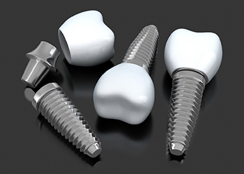 three dental implants with abutments and crowns lying on a table 