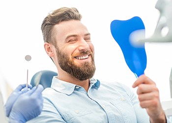 bearded man admiring his new smile with dental implants 