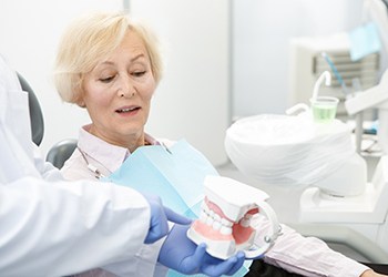 dentist showing a patient how dental implants work 