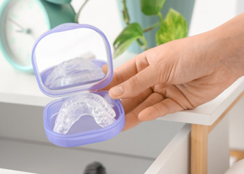 Hand holding nightguard in its storage case