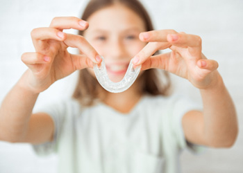 Happy patient holding her bruxism nightguard