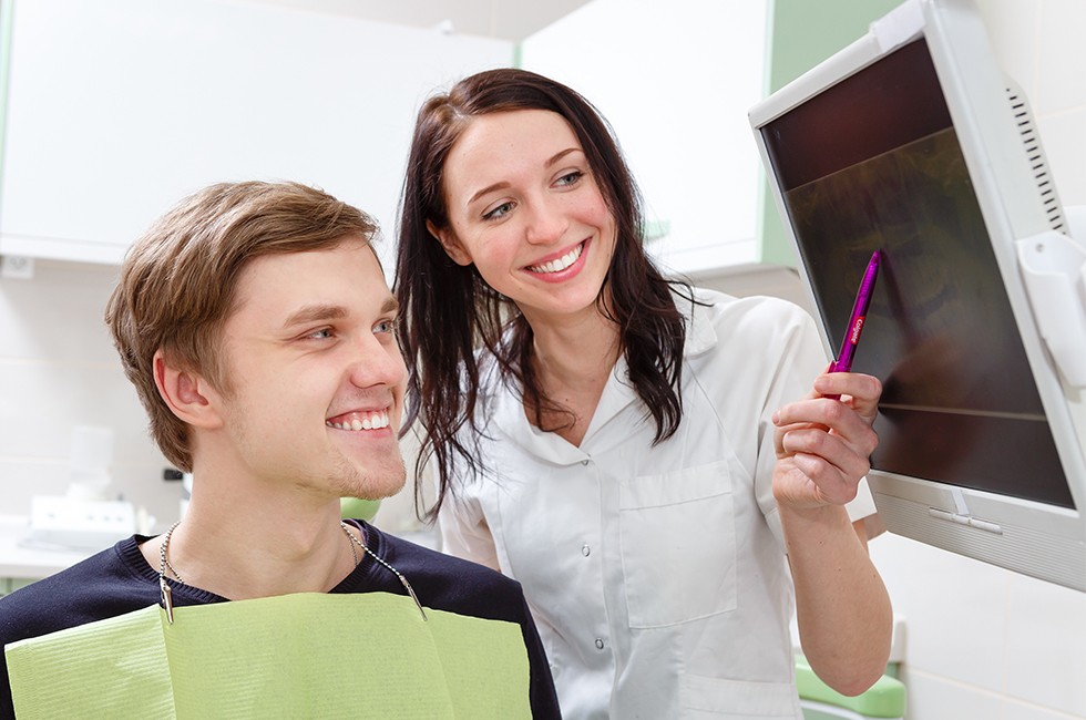 Dentist and patient looking at x-rays on computer monitor