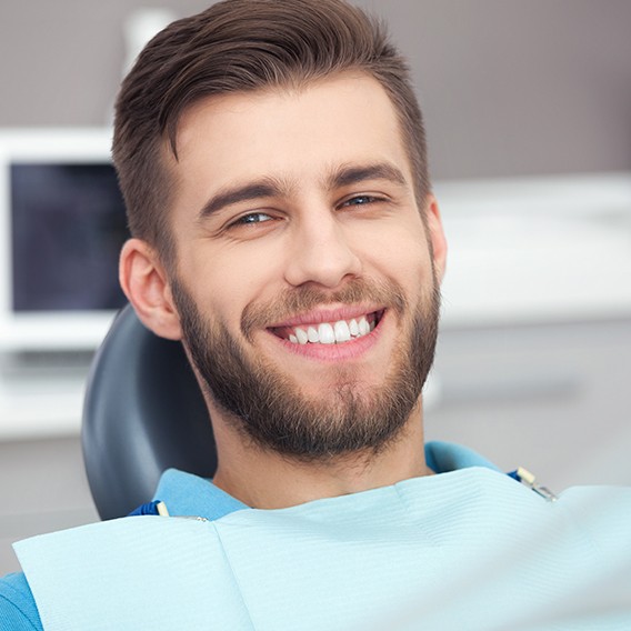 Young bearded man smiling in dental chair