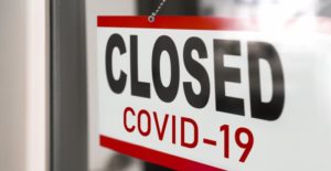 Door sign reading "CLOSED COVID-19" until your Midland dentist reopens. 