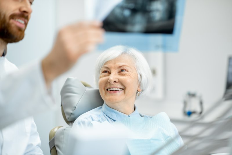 Dentist showing smiling woman X-ray