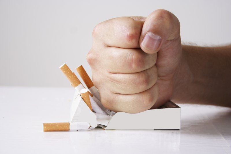 Fist crushing box of cigarettes