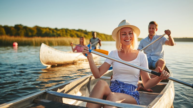 Smiling couple canoeing with friends on the lake