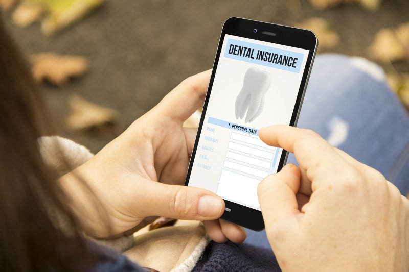 young woman looking at dental insurance on phone