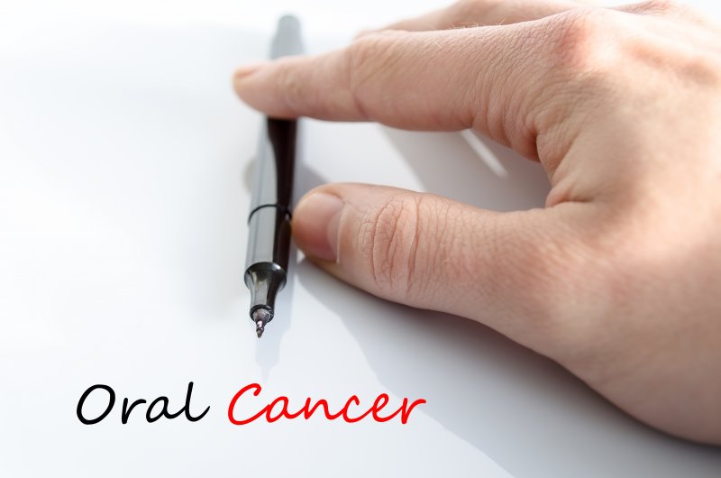 hand with a pen and words oral cancer