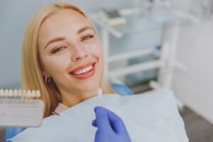 Woman looking at veneers in dentist's chair.