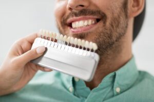 Dentist holding up veneers to patient.